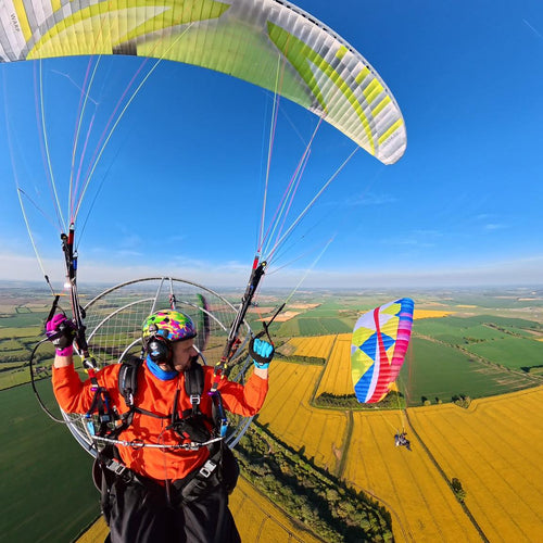 Student and Trainer paramotoring over a landscape with a clear blue sky