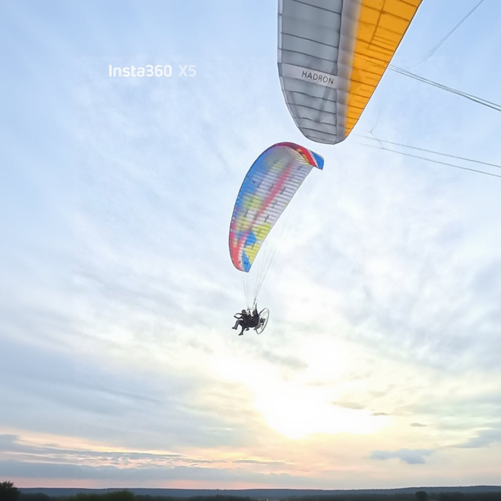 Two paramotor flying over a landscape with a clear sky.